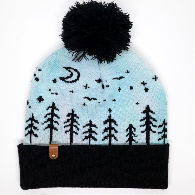 Hand-dyed kids winter beanie fading from lavender to light blue with black pom-pom and forest design.
