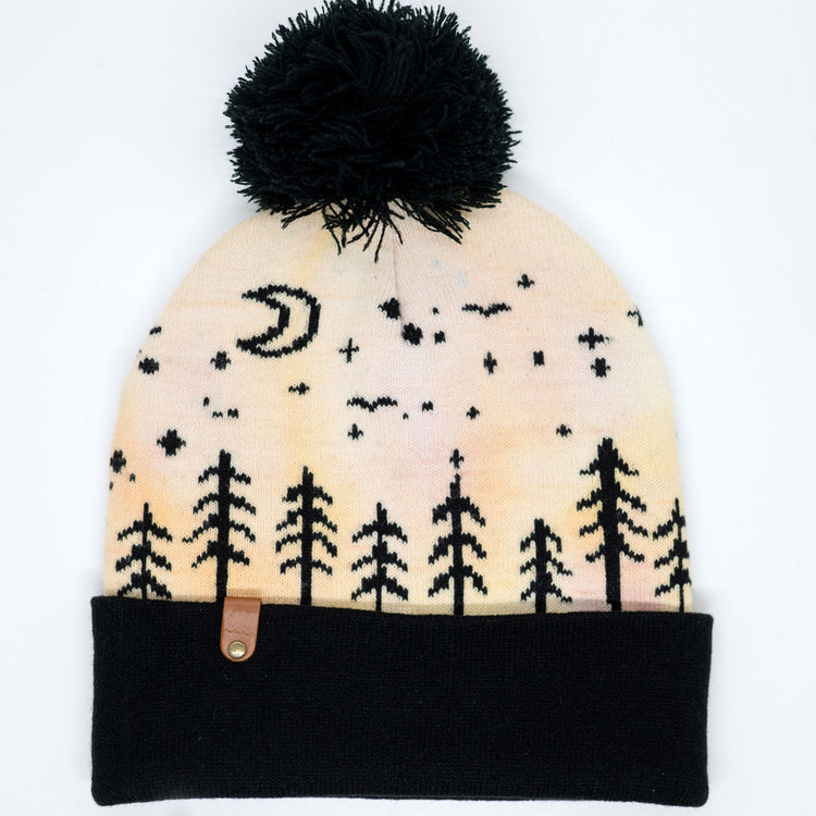 Cream and peach hand-dyed kids winter beanie with black pom-pom, folded cuff and moonlit forest pattern.