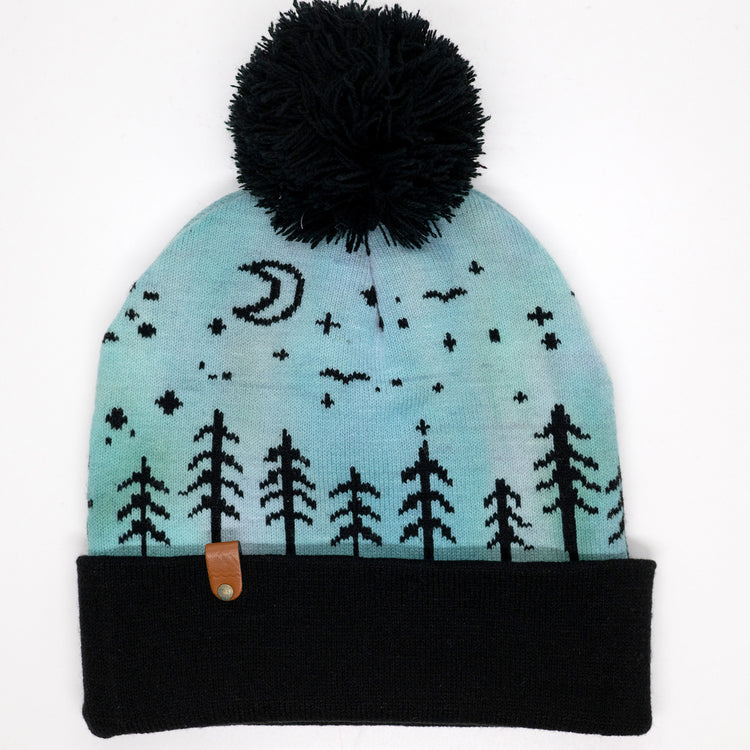 Hand-dyed kids winter beanie fading from lavender to light blue with black pom-pom and forest design.