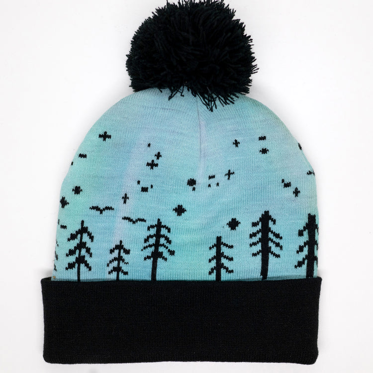 Hand-dyed kids winter beanie fading from lavender to light blue with black pom-pom and forest design.