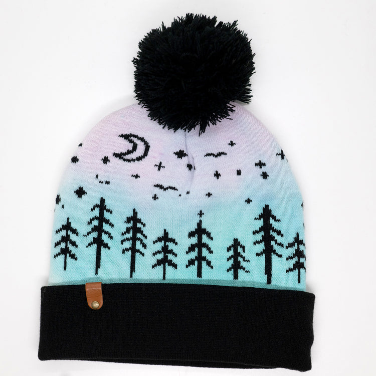 Hand-dyed kids winter beanie fading from pink to light blue with black pom-pom and forest design.