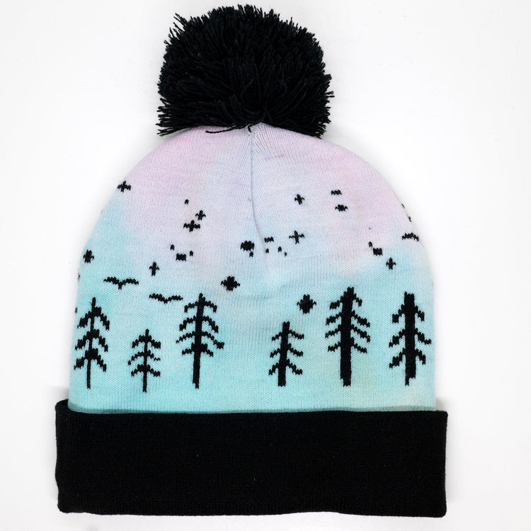 Hand-dyed kids winter beanie fading from pink to light blue with black pom-pom and forest design.