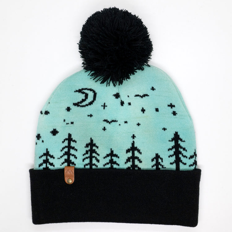 Hand-dyed kids winter beanie fading from lavender to light blue with black pom-pom and forest design.