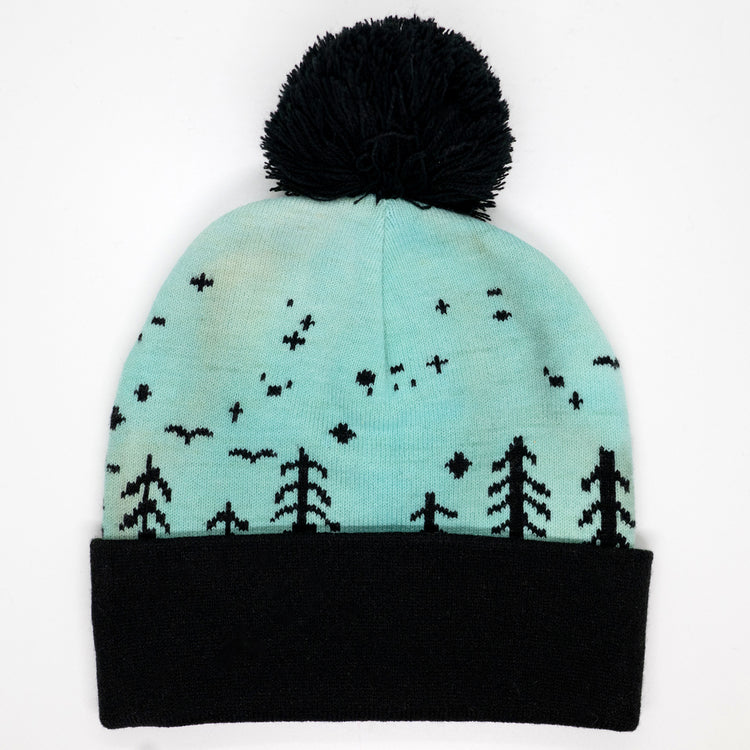 Hand-dyed kids winter beanie fading from lavender to light blue with black pom-pom and forest design.