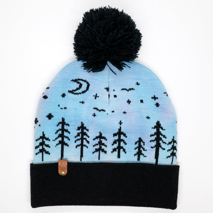 Hand-dyed kids winter beanie fading from lavender to light blue with black pom-pom and forest design.
