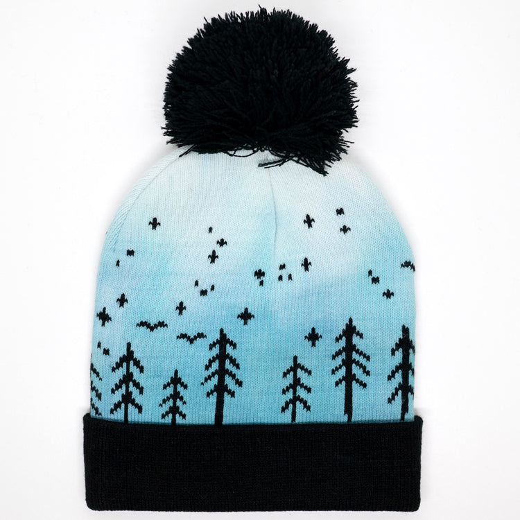 Hand-dyed kids winter beanie fading from blue to white with black pom-pom and forest design.