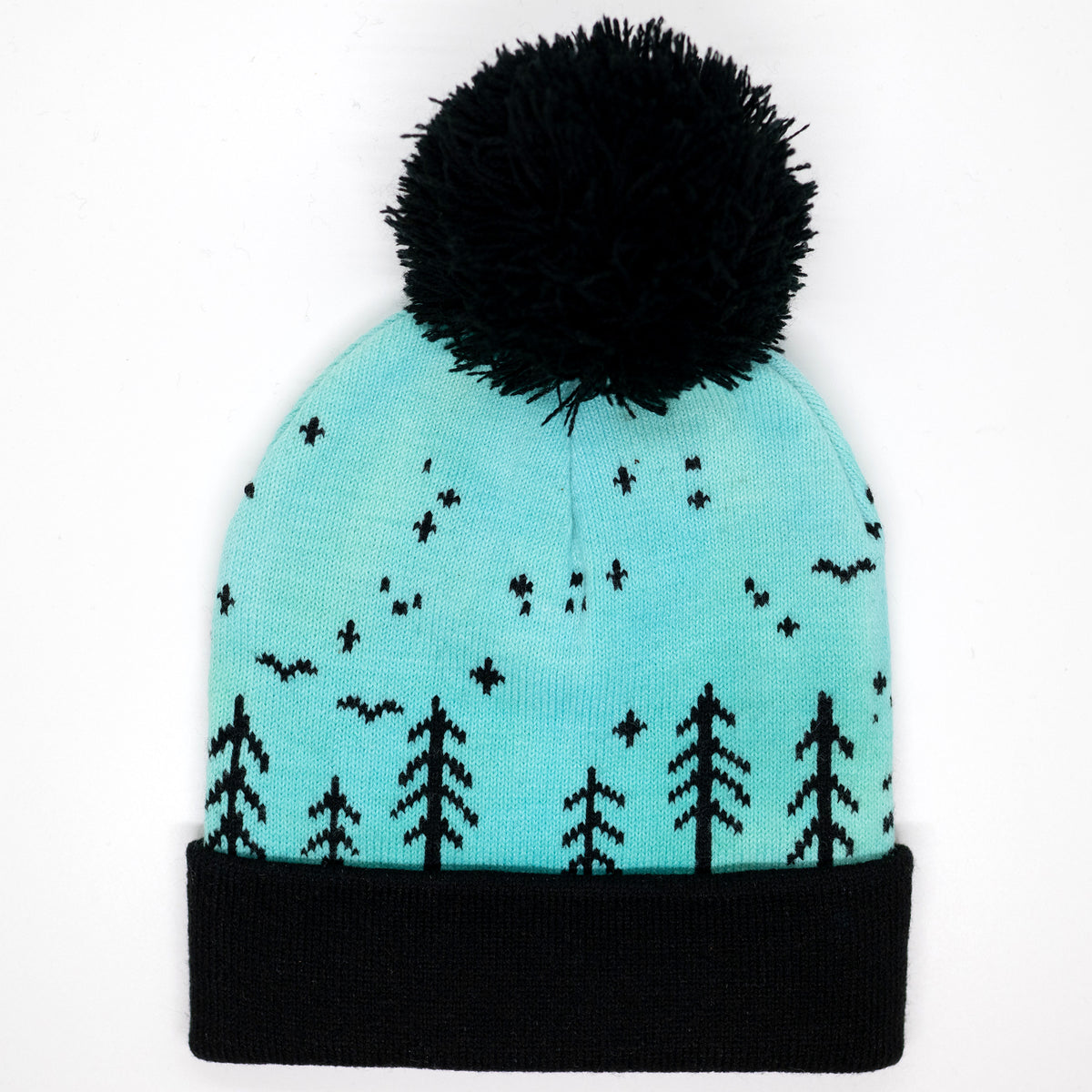 Hand-dyed kids winter beanie fading from blue to green with black pom-pom and forest design.