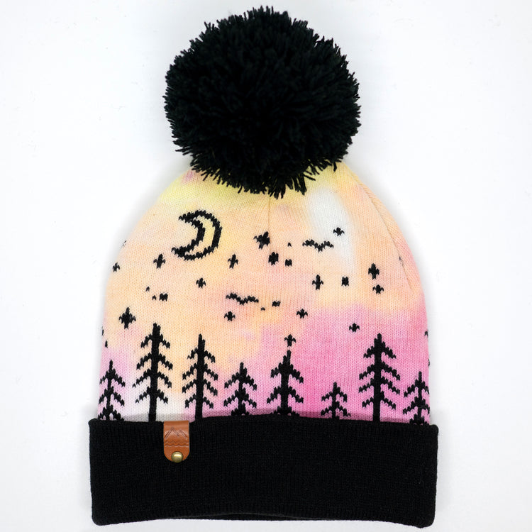 Hand-dyed pink and yellow kids winter beanie with black pom-pom, folded cuff, pine trees, moon and stars.
