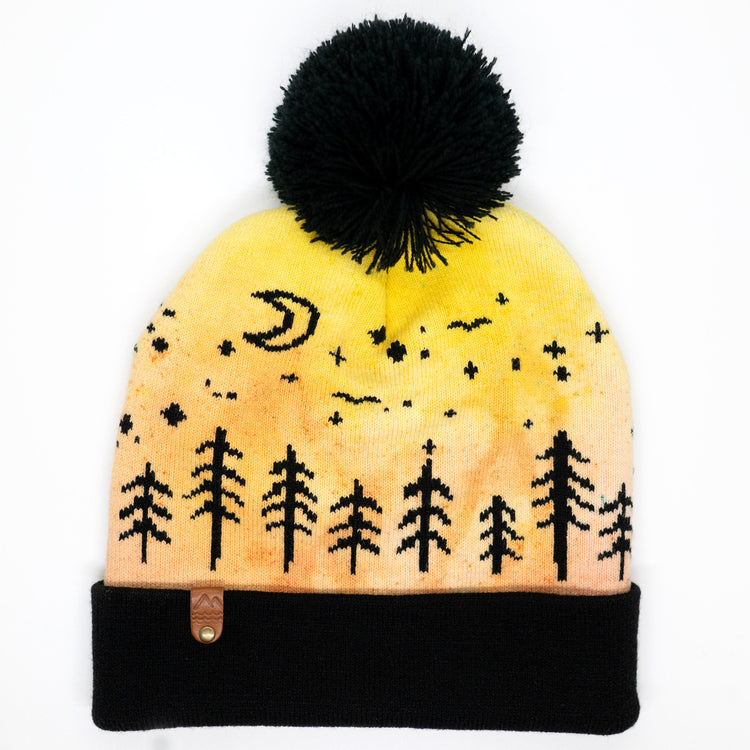 Hand-dyed kids winter beanie fading from yellow to orange with black pom-pom and forest design.