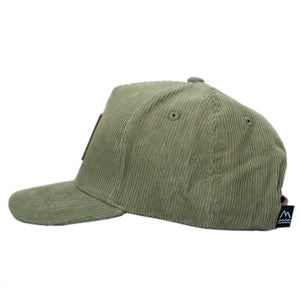 Green corduroy hat for toddlers and children with a brown leather patch.