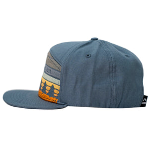 Get lost embroidered woodsy kids hat for hikers, outdoor-lovers, and just cool kids. Subtle sunset design with pine trees on a slate blue flat brim children's cap.