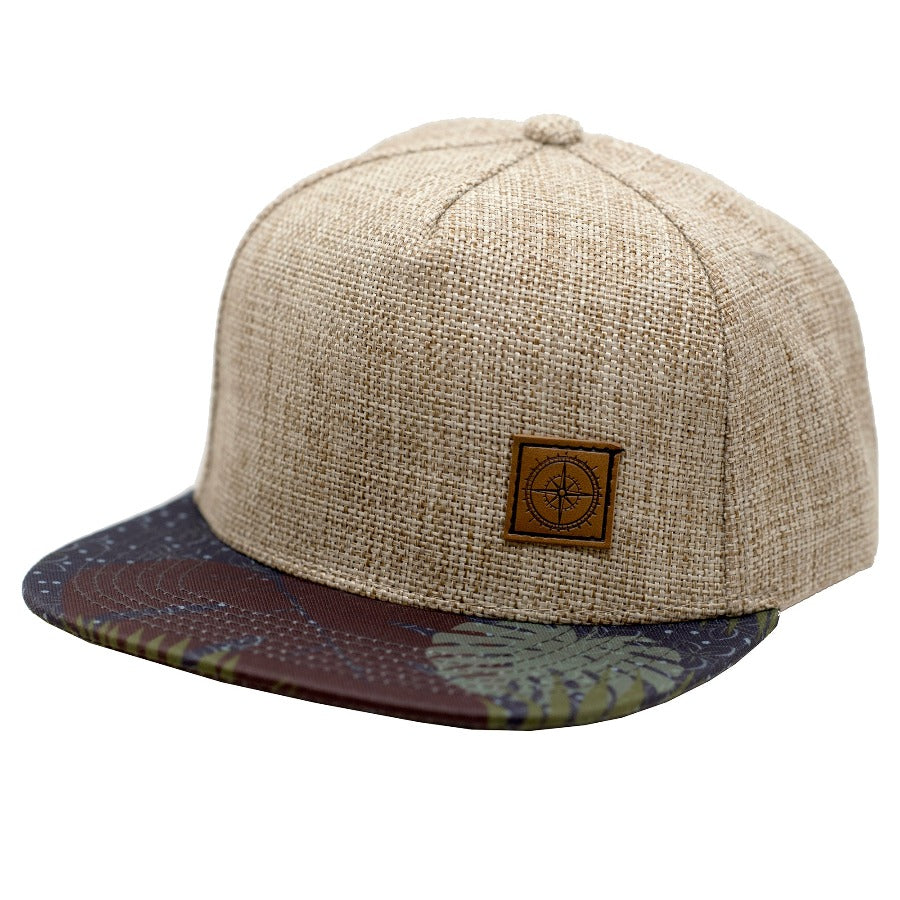 Tropical print children's hat with a linen crown and brown leather patch stamped with a compass design. 